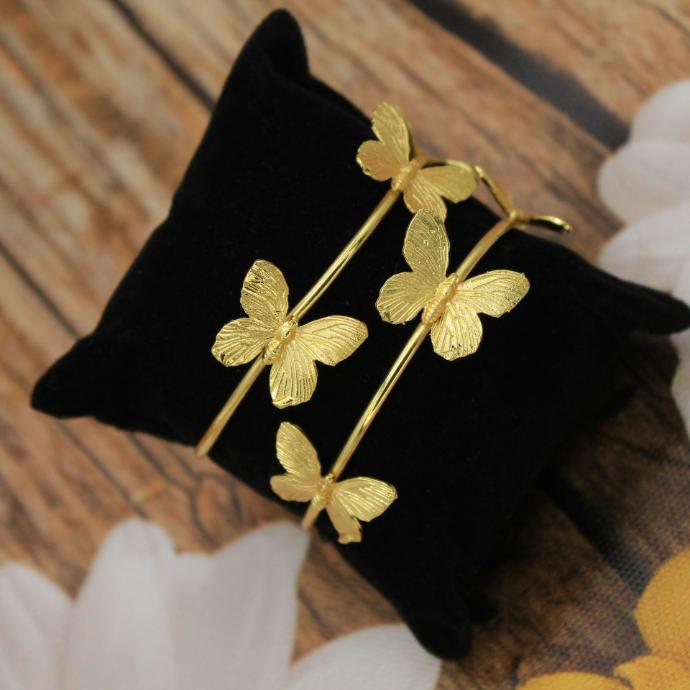 a pair of gold plated flowers on a black velvet pillow